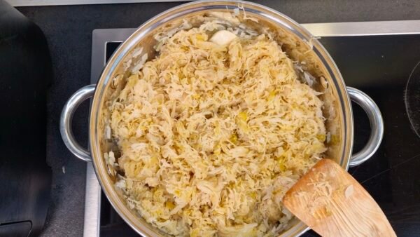 Adding sauerkraut, wine, water, and seasonings to the pot