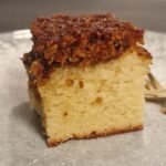 Slice of Danish dream cake with a golden sponge base and browned coconut topping
