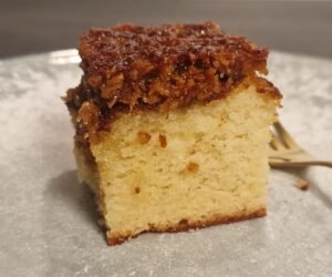Slice of Danish dream cake with a golden sponge base and browned coconut topping