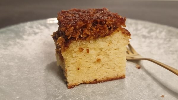 Slice of Danish dream cake with a golden sponge base and browned coconut topping
