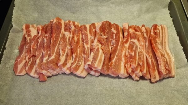 Raw pork belly slices arranged in a baking pan
