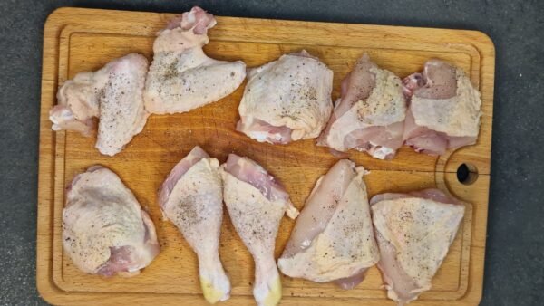 Chicken pieces seasoned with salt and pepper on a board