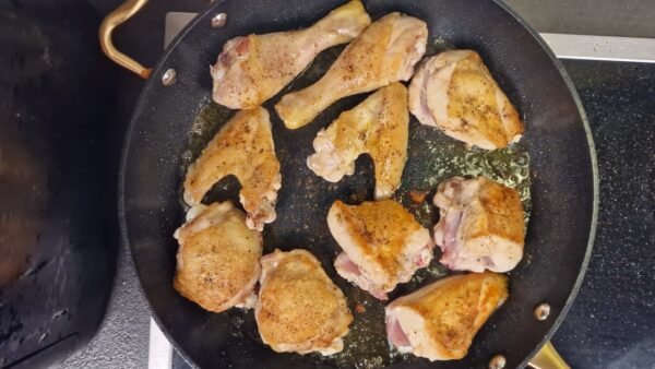 Chicken pieces browning in olive oil in a skillet