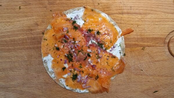 Smoked salmon lompe topped with red onion, dill, and black pepper