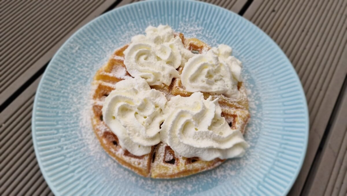 Waffle topped with whipped cream and powdered sugar
